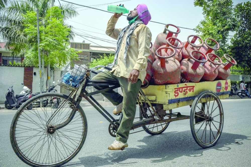 بائع الغاز يتجرع مياه الشرب وسط موجة حر بالهند "أ ف ب"