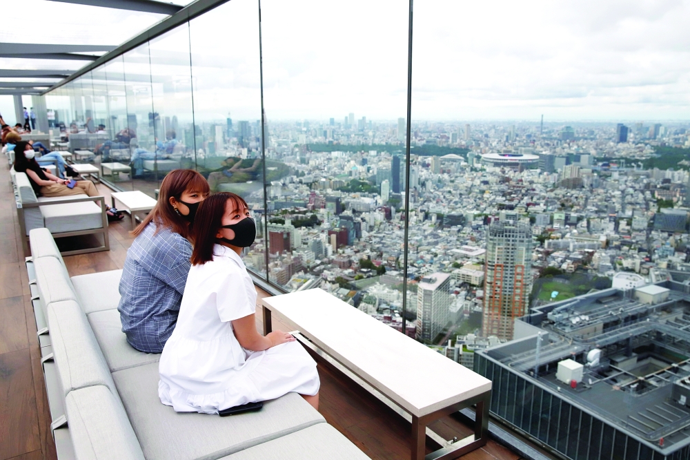 نساء يرتدين أقنعة يشاهدن طوكيو من الأعلى في صالة شيبويا سكاي الخارجية، وسط تفشي فيروس كورونا في طوكيو 2021. رويترز 