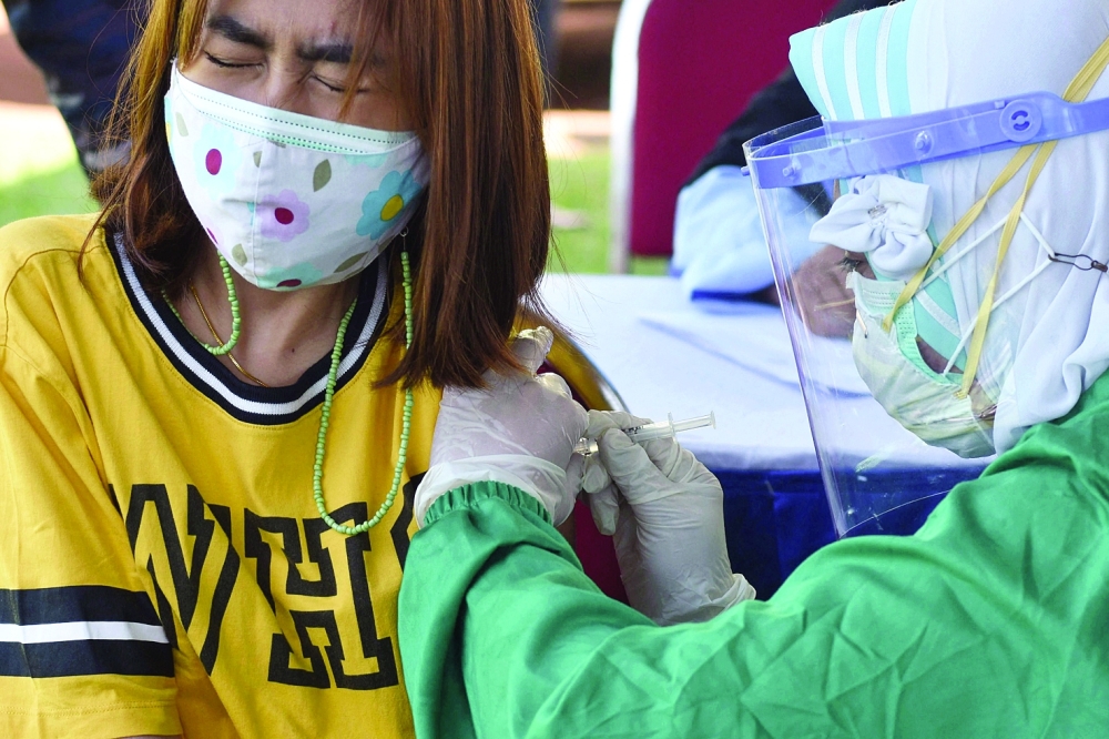 امرأة تتلقى لقاح كورونا في مالانج بجاوة الشرقية باندونيسيا امس خلال برامج التطعيم الجماعي. أ.ف.ب 