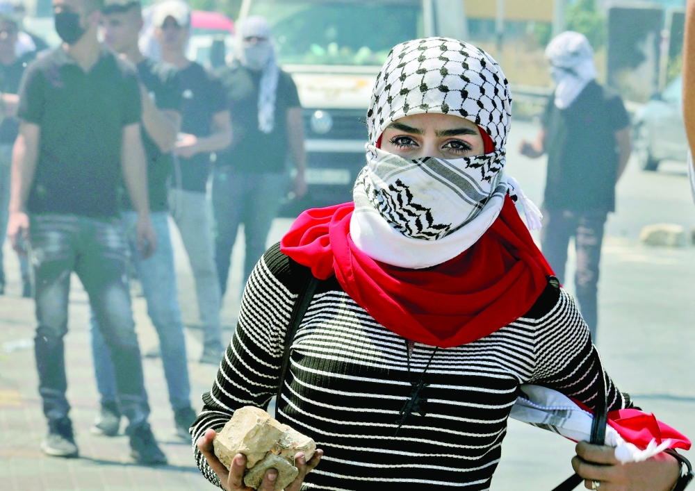 طالبة فلسطينية من جامعة بيرزيت تحمل حجرا لرشق قوات الأمن الإسرائيلية خلال مظاهرة بالقرب من مستوطنة بيت إيل الإسرائيلية أمس.أ.ف.ب 
