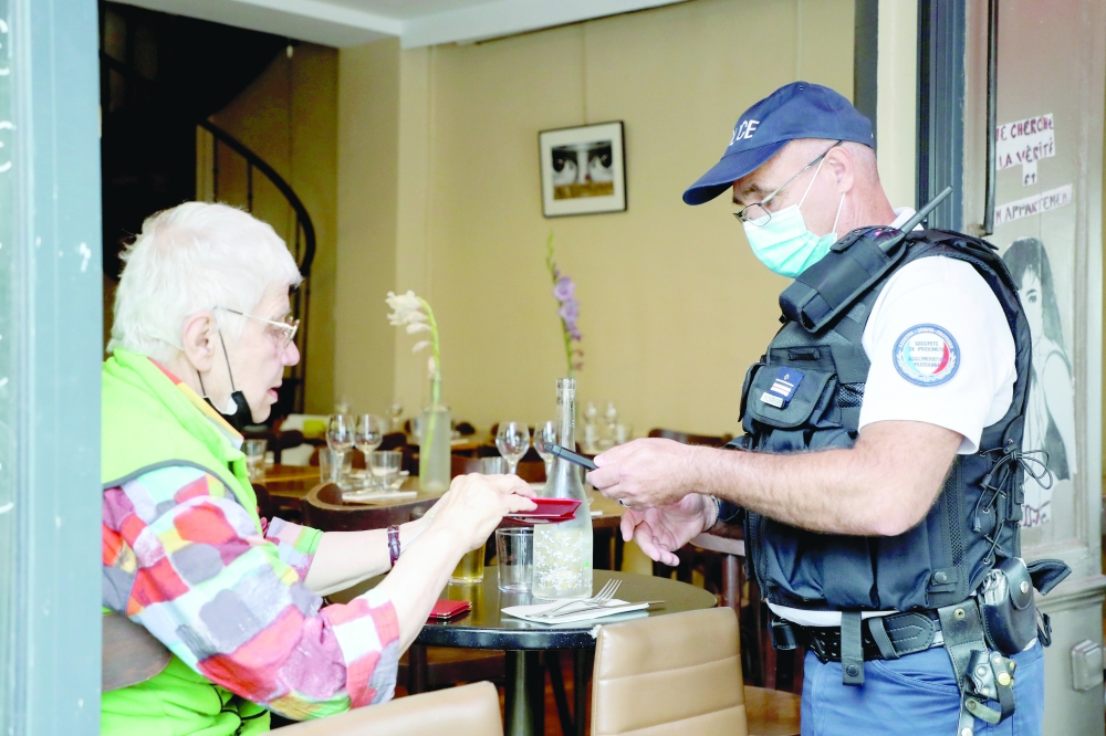 ضابط شرطة فرنسي يتفقد امتثال تصريح المرور الصحي لعميل مطعم حيث من المتوقع تكثيف الفحوصات على تنفيذ التصريح الصحي في باريس .رويترز 
