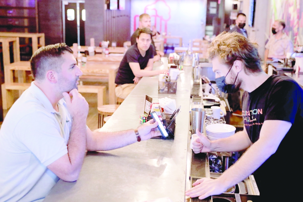 يُظهر أحد العملاء دليلًا على التطعيم لعامل في كلينتون هول حيث بدأ تفويض اللقاح أثناء تفشي مرض فيروس كورونا (COVID-19) في مانهاتن ، مدينة نيويورك