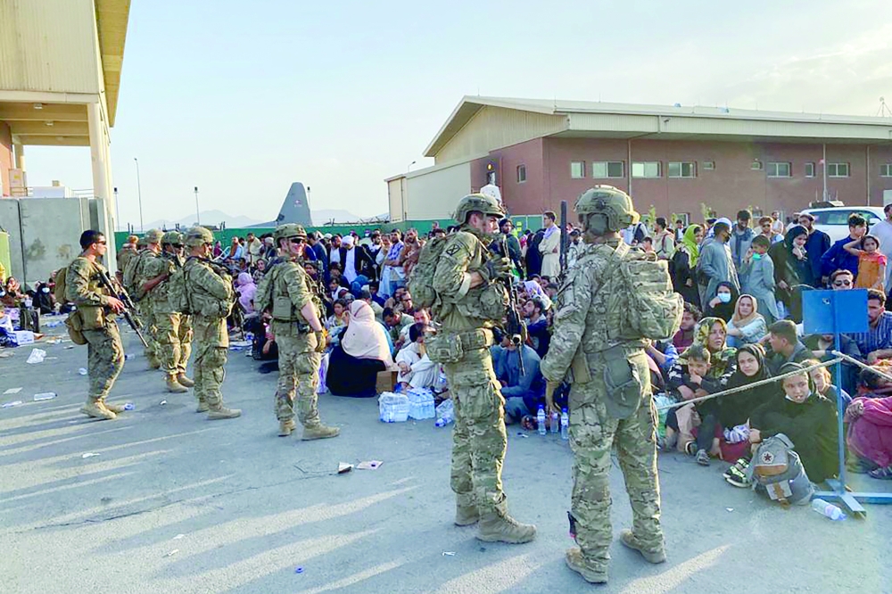 جنود أمريكيون وبجوارهم ركاب أفغان في المطار العسكري بكابول أمس.  "أ ف ب"