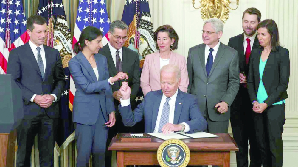 لينا خان رئيسة لجنة التجارة الفيدرالية تمسك بطرف القلم مع الرئيس الأمريكي جون بايدن