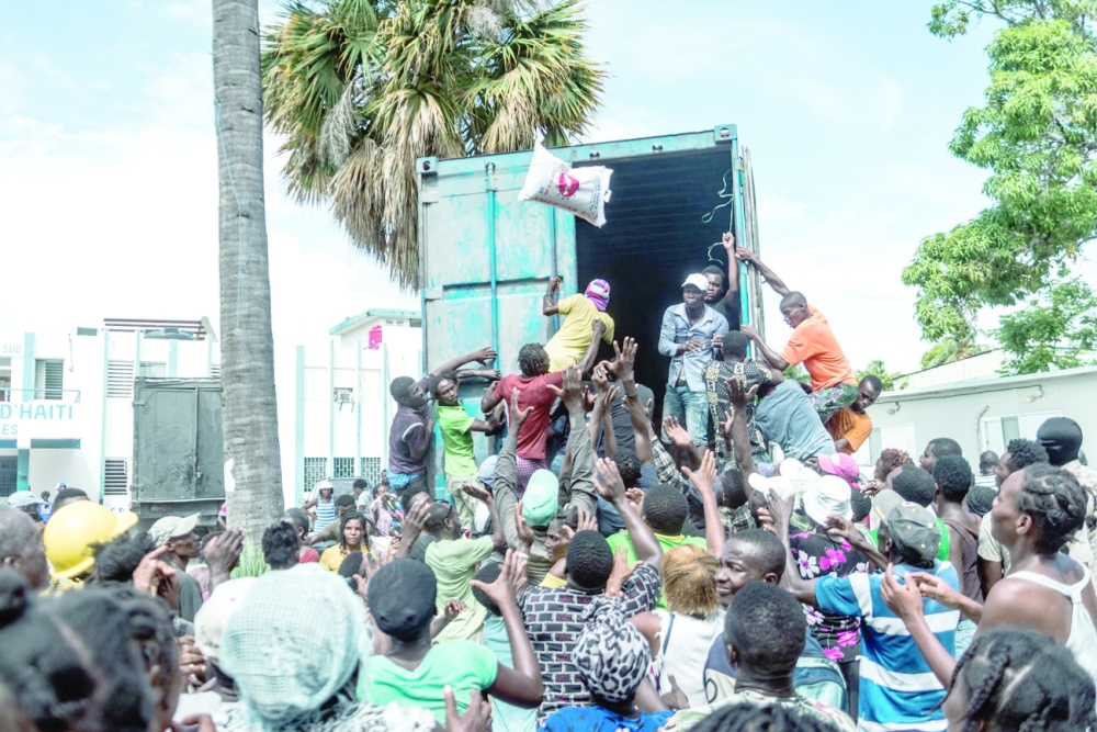 صورة توضح مشاهد الفوضى  في ليس كايس، إحدى أكثر المدن تضررا بالزلزال، فيما  أكياس الأرز تُلقى على حشود صاخبة