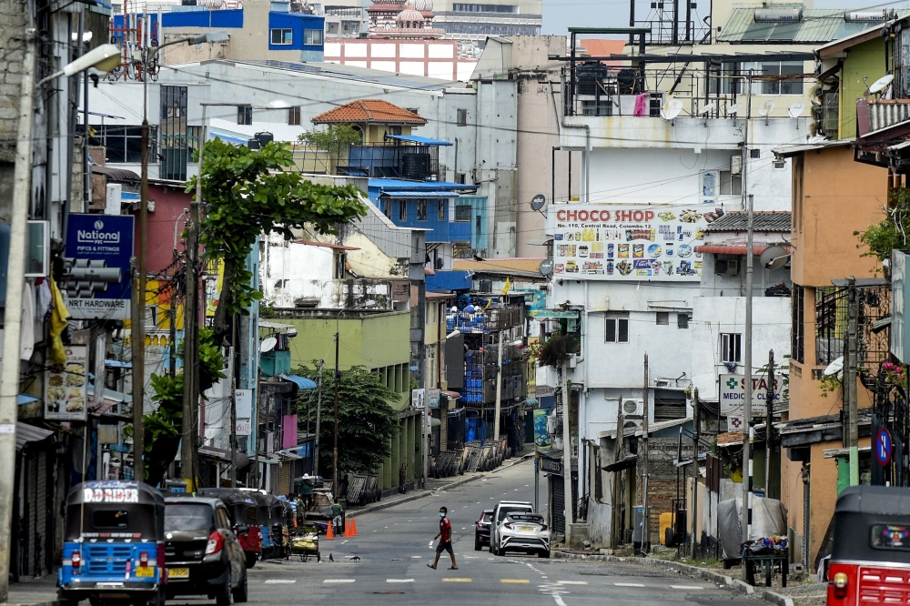 منظر عام يظهر رجلاً يعبر شارعًا مهجورًا خلال إغلاق على مستوى البلاد لمدة 10 أيام تم فرضه للحد من انتشار كورونا في كولومبو