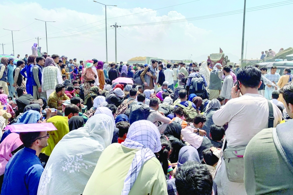 تجمع الشعب الأفغاني على طول طريق أثناء انتظارهم لركوب طائرة عسكرية لمغادرة البلاد، في مطار عسكري في كابول