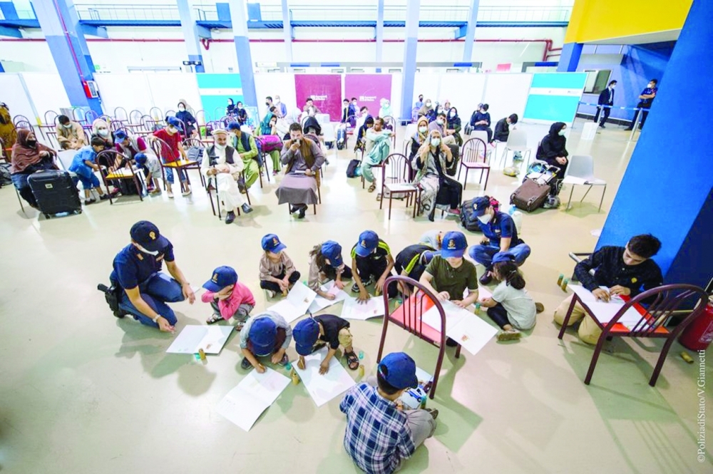 أطفال أفغان يلعبون مع ضابط شرطة عند وصولهم إلى مطار فيوميتشينو في روما، إيطاليا