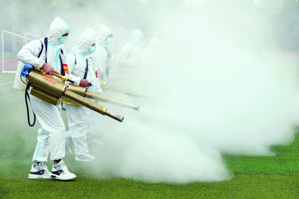 عدد من الموظفين في مجال الصحة يقومون برش مطهر في احد المدارس الصينية قبل بدء الفصل الدراسي الجديد  شرق الصين امس . أ.ف.ب