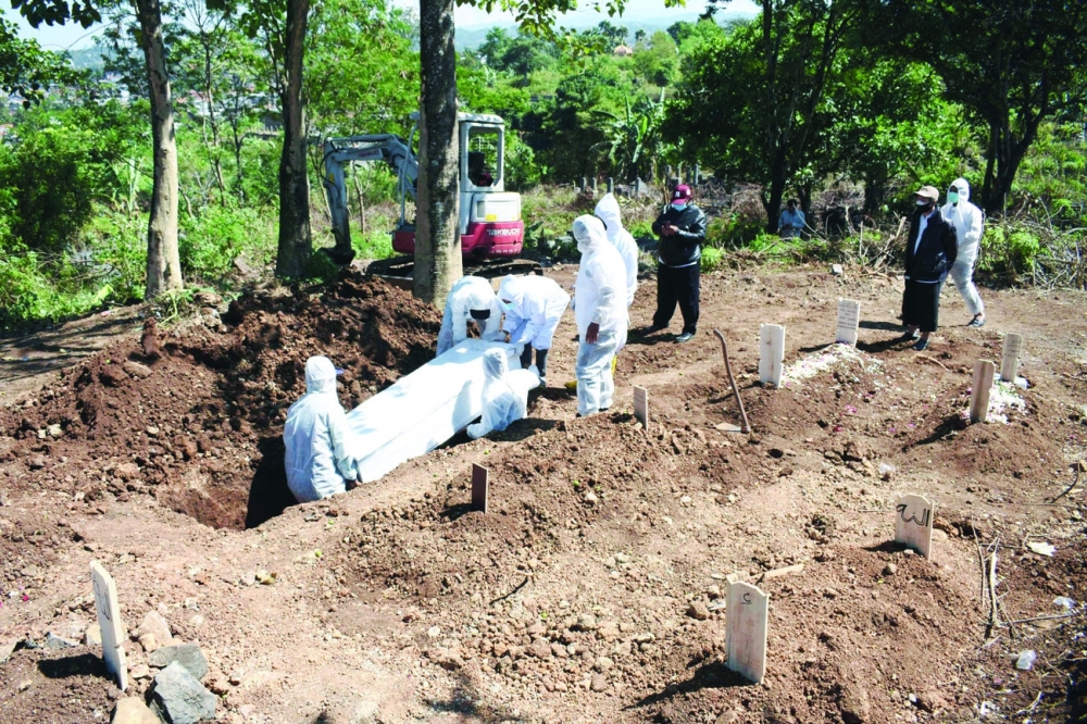 أفراد الأسرة وسائقو سيارات الإسعاف يدفنون ضحية فيروس كورونا في مقبرة بعد أن أضرب حفارو القبور وقالوا إنهم لم يتلقوا رواتب من الحكومة المحلية في باندونج باندونيسيا . أ.ف.ب  