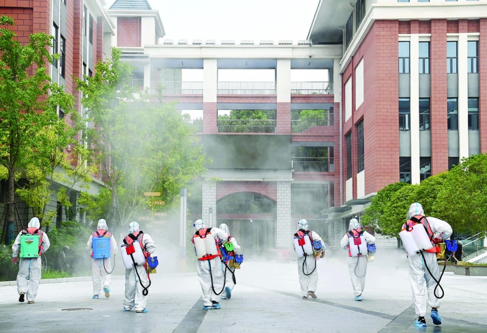 عمال يرتدون بدلات واقية يقومون بتطهير مجمع مدرسة ابتدائية قبل إعادة فتح المدارس للفصل الدراسي القادم ، في أعقاب تفشي   فيروس كورونا  في ووهان  بمقاطعة هوبي . رويترز 