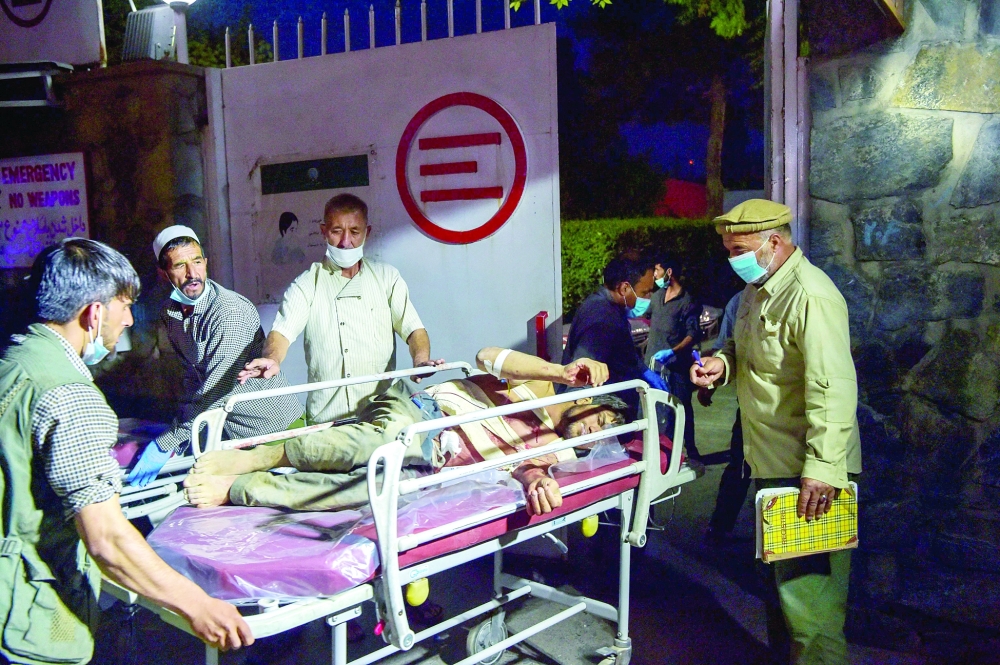 طواقم طبية تنقل احد الجرحى، بعد انفجار بالقرب من مطار كابول، امس.   ا ف ب