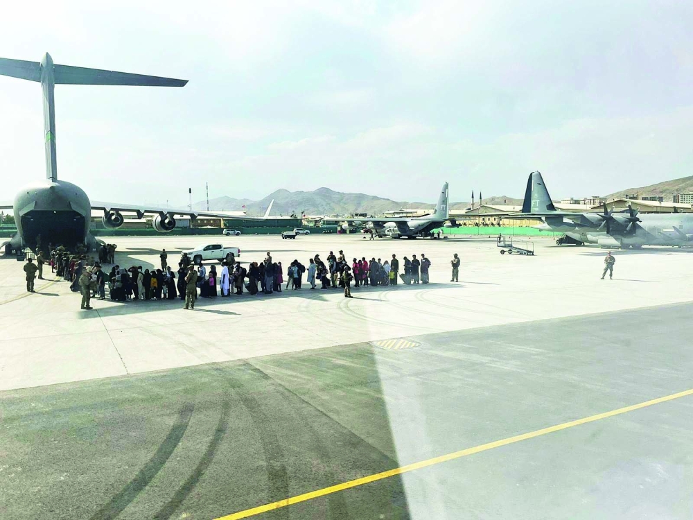 يصطف مجموعة كبيرة من الأفغان الذين يتم إجلاؤهم عبر إحدى الطائرات العسكرية الايطالية من مطار كابول