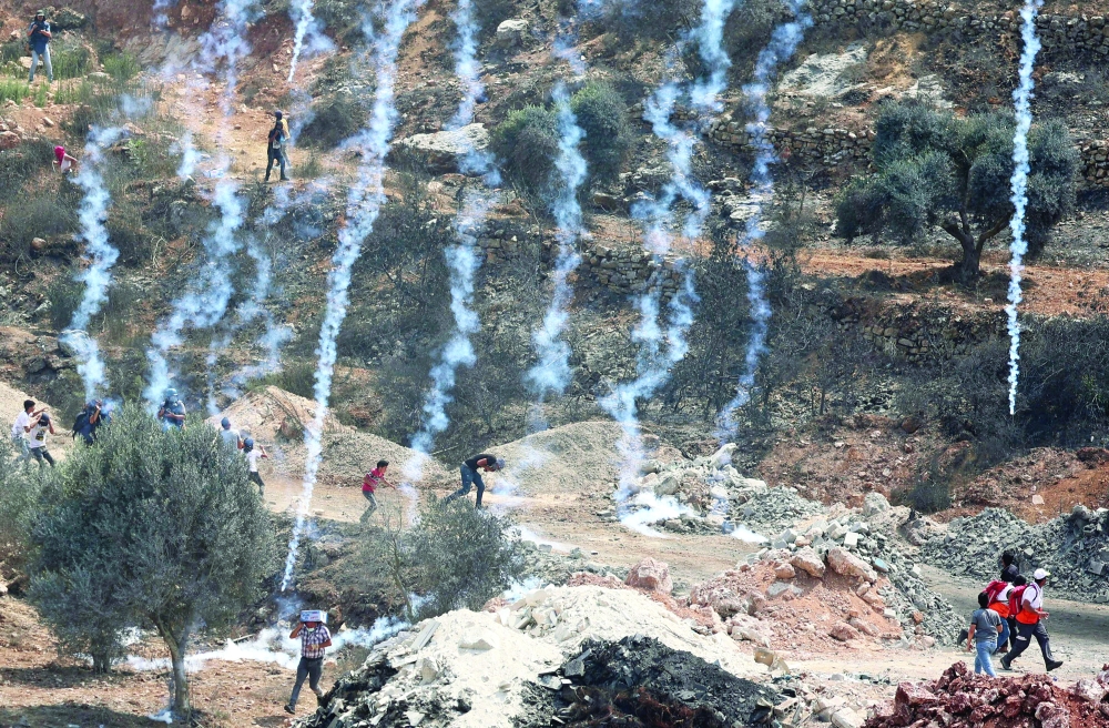متظاهرون فلسطينيون يهربون من قنابل الغاز المسيل للدموع التي أطلقتها القوات الاحتلال خلال مواجهات بشمال الضفة الغربية المحتلة. أ.ف.ب 