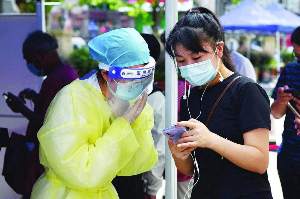  عاملة في المجال الطبي تساعد امرأة على التسجيل لاختبار فيروس كورونا في مستشفى في شنجهاي امس. أ.ف. ب 