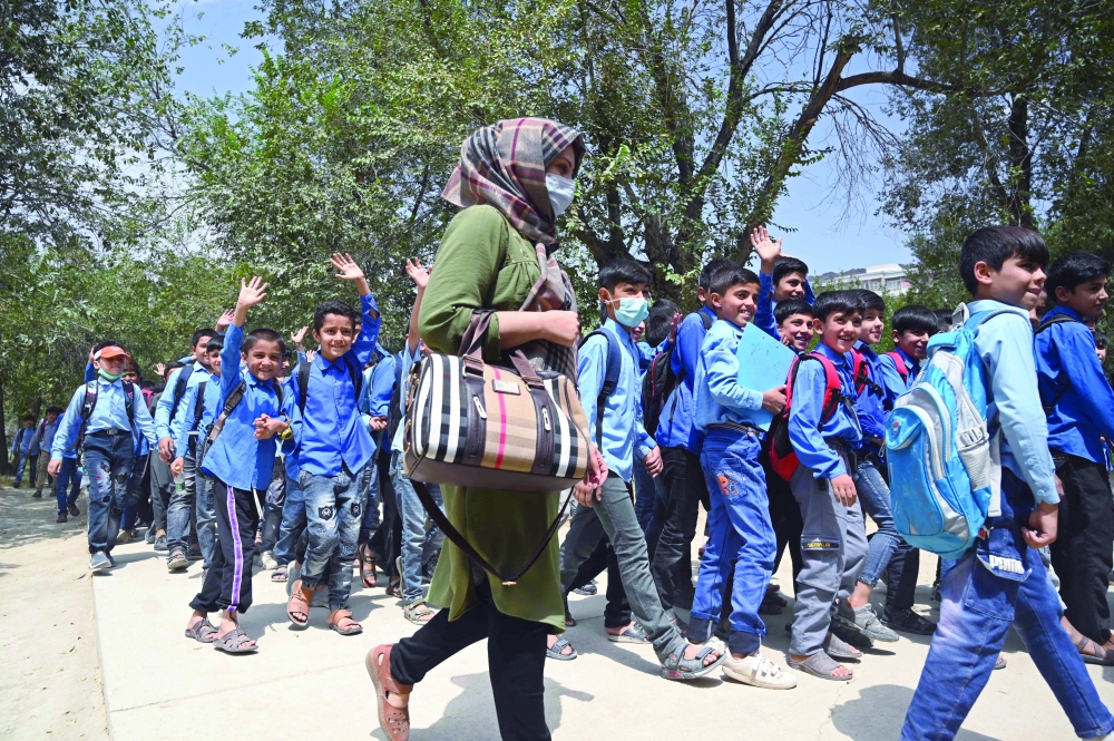 معلمة تسير مع الطلاب أثناء مغادرتهم بعد التحاقهم بالمدرسة الإعدادية الحكومية في كابول.أ.ف.ب 
