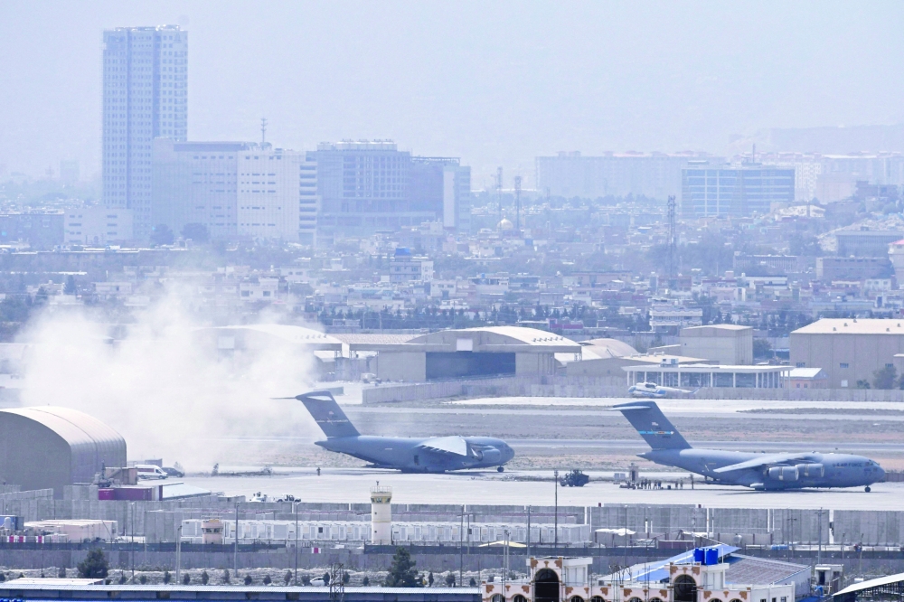 جنود أمريكيون يقفون على مدرج المطار بينما تستعد طائرة تابعة للقوات الجوية الأمريكية (L) للإقلاع من مطار كابول.أ.ف.ب