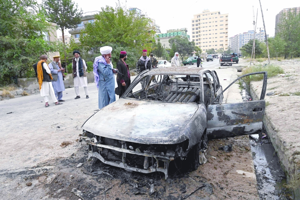 مقاتلو طالبان يحققون في إصابة سيارة متضررة بعد إطلاق صواريخ متعددة في كابول أمس.أ.ف.ب