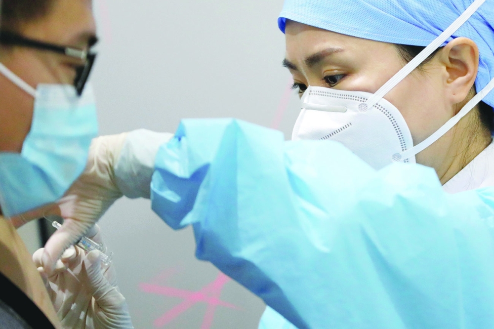 عاملة طبية تستعد لإعطاء جرعة من لقاح ورونا لرجل في موقع للتلقيح في بكين. رويترز 