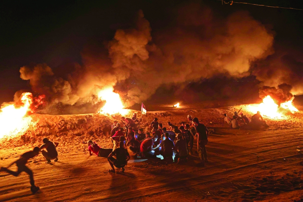 مجموعة من الفلسطنيين خلال مظاهرة ليلية على طول السياج الحدودي مع إسرائيل، مطالبين بإنهاء الحصار الإسرائيلي. أ.ف. ب 