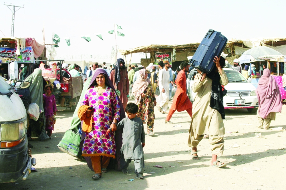  عائلات افغانية يحملون أمتعتهم يعبرون الحدود إلى باكستان عند نقطة عبور بوابة الصداقة في بلدة شامان الحدودية بين باكستان وأفغانستان امس. رويترز 