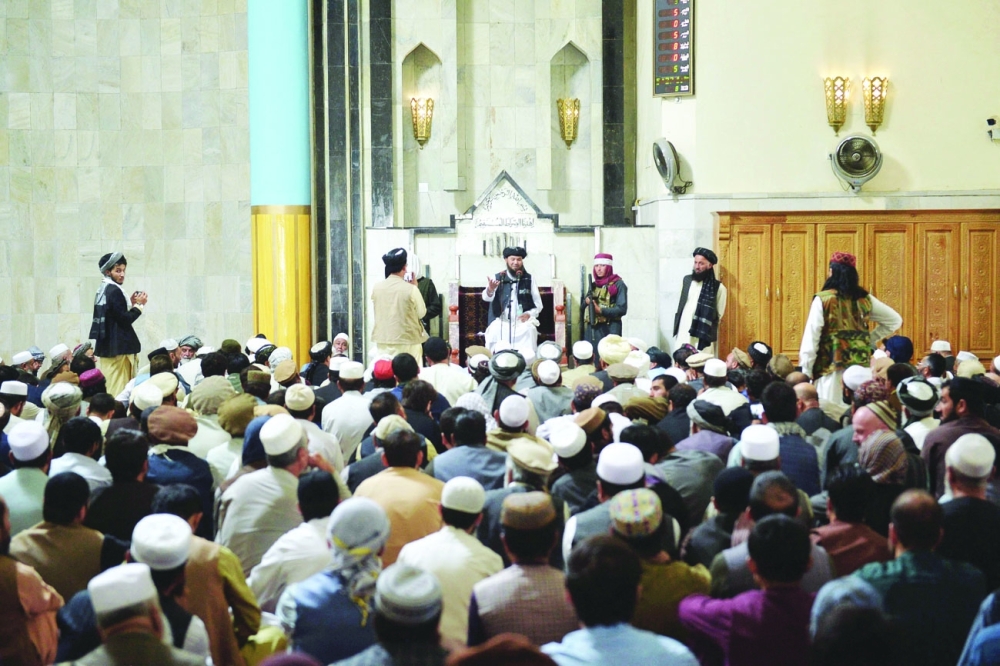 مقاتلو طالبان المسلحين يقفون بجانب زعيم ديني الملا (وسط الصورة) يتحدث خلال صلاة الجمعة في مسجد بول خيشتي في كابول امس. أ.ف.ب 