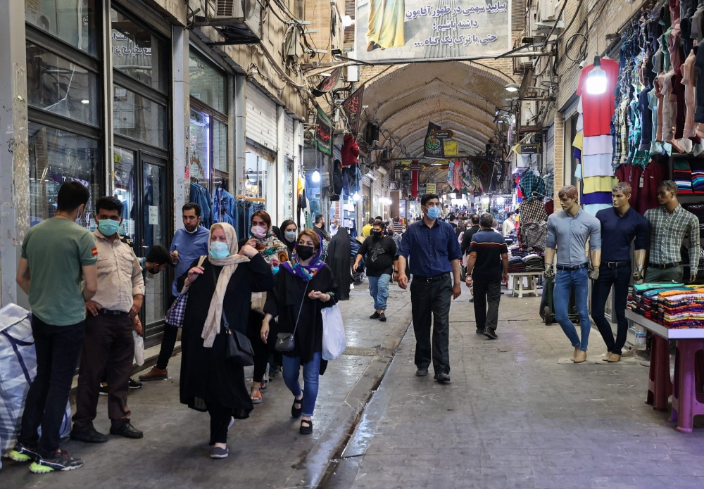 إيرانيون يرتدون أقنعة واقية من كوفيد -19 ، يتسوقون في البازار الكبير بالعاصمة الإيرانية طهران امس . أ.ف. ب 