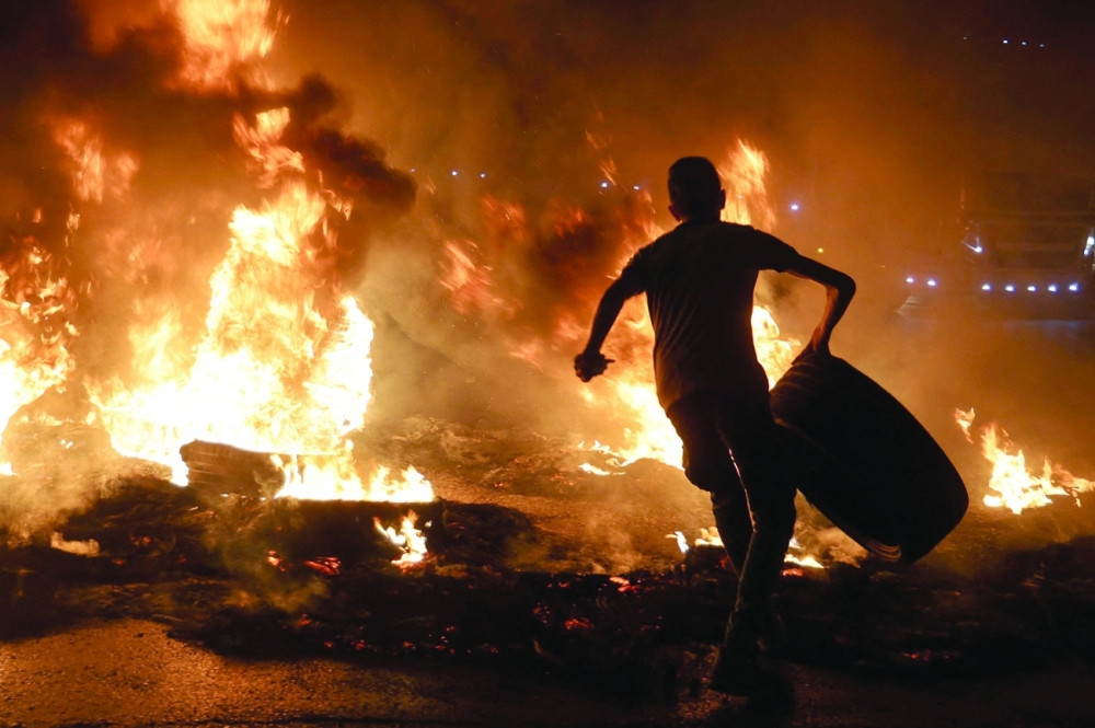 شاب فلسطيني يحمل إطارًا قبل إشعال النار فيه ، خلال مواجهات مع قوات الأمن الإسرائيلية عقب مظاهرة لدعم الأسرى الفلسطينيين المحتجزين في السجون الإسرائيلية ، عند حاجز حوارة بالقرب من مدينة نابلس بالضفة الغربية أ.ف.ب