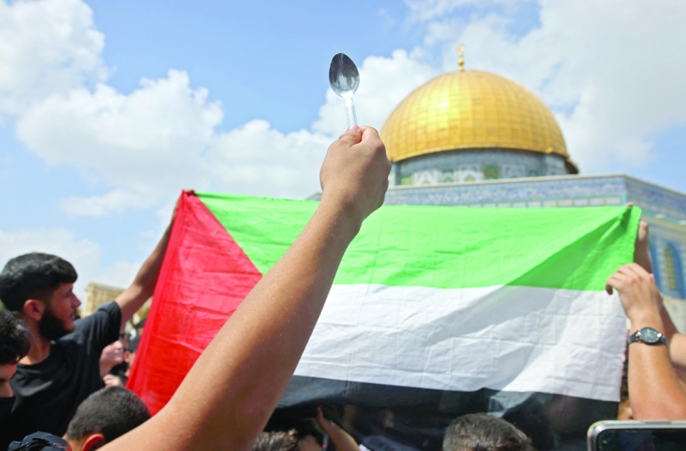 شخص يحمل ملعقة ، يقال إنها أداة الحفر التي استخدمها ستة سجناء فلسطينيين فروا من سجن جلبوع الإسرائيلي ، خلال تجمع أمام مسجد قبة الصخرة بعد صلاة الجمعة في مجمع المسجد الأقصى بالقدس امس . أ.ف.ب  