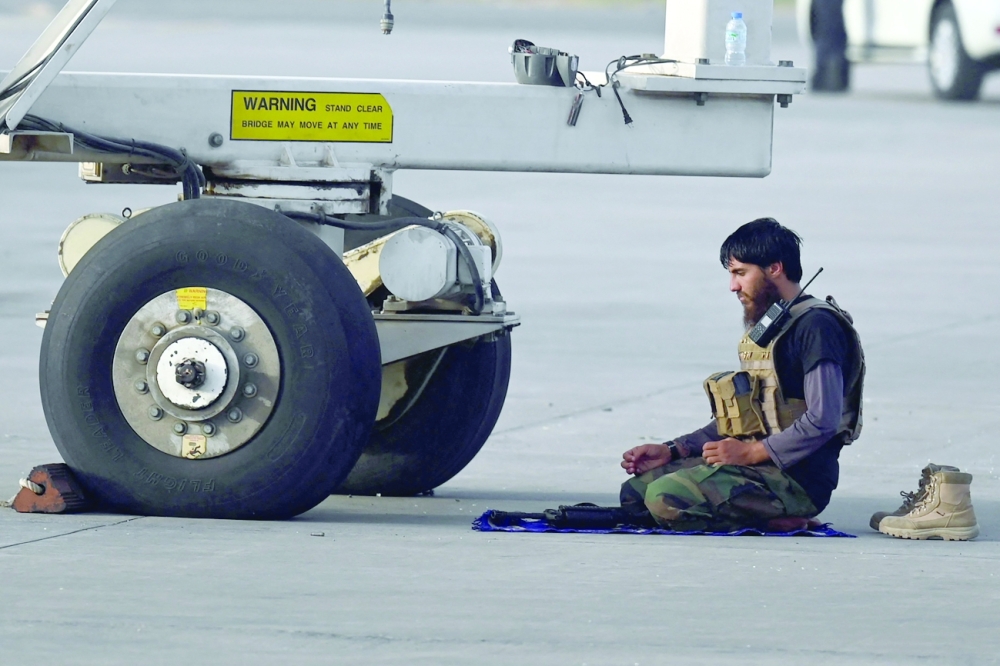 أحد أفراد طالبان يصلي العشاء بالقرب من طائرة في كابول. "أ ف ب"