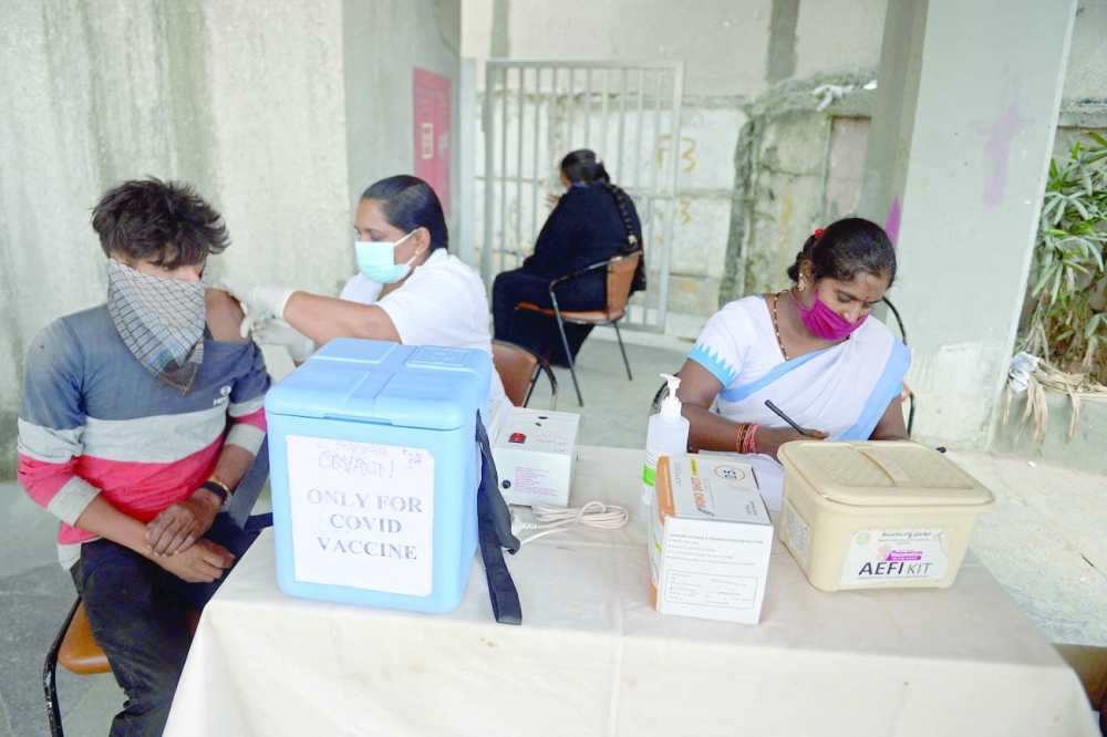 عاملة صحية تقوم بتلقيح رجل بجرعة من لقاح كوفيد -19  في حملة تطعيم بحيدر أباد أمس.   (أ ف ب)