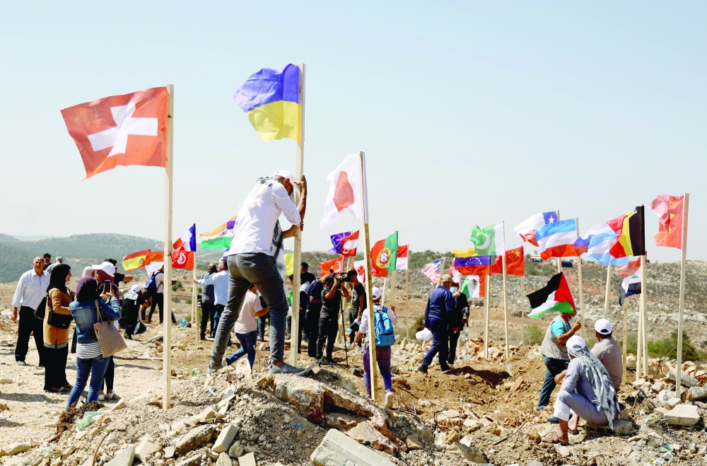 نشطاء فلسطينيون يرفعون أعلام الدول التي تعارض المستوطنات غير القانونية في المخيم الذي أقيم حديثا والذي يطلق عليه اسم مخيم الأمم المتحدة ، بالقرب من مستوطنة آرييل الإسرائيلية ، غربي بلدة سلفيت بالضفة الغربية المحتلة.أ.ف.ب