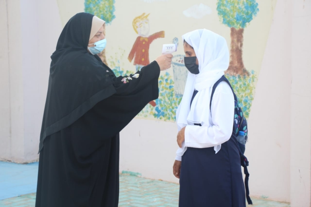 اجراء الفحص لقياس درجة الحرارة للطالبات 