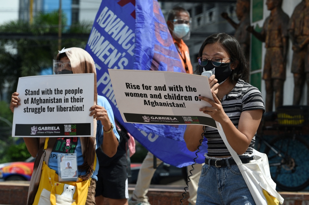 متظاهرون يحملون لافتات لدعم النساء والأطفال الأفغان في  إحدى ضواحي مانيلا أمس.  (أ ف ب)