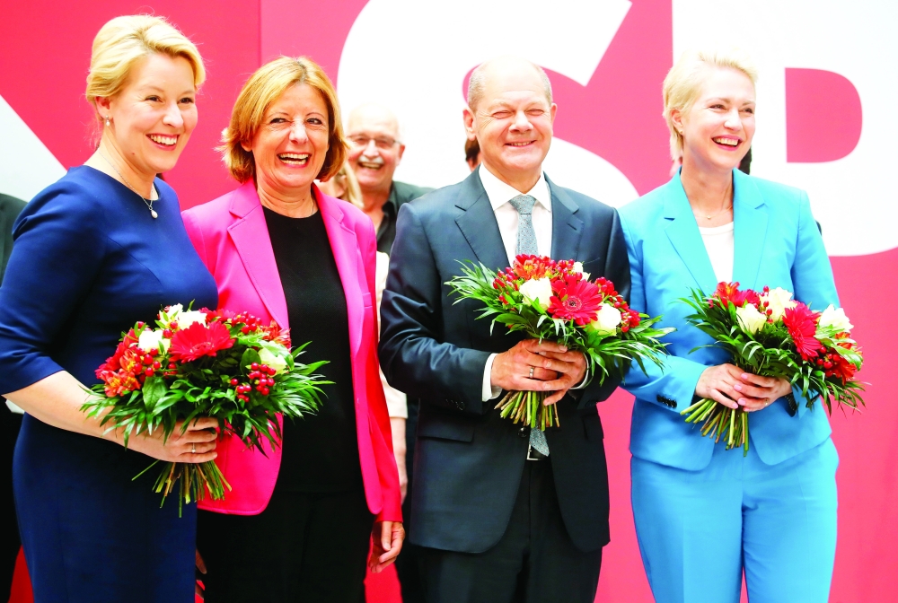    قادة الحزب الإشتراكي يحملون باقات الزهور بعد يوم من فوزهم بالانتخابات العامة في برلين أمس. (رويترز)   