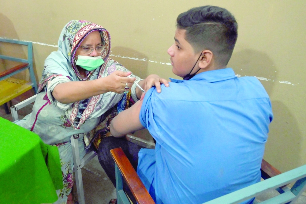 ممرضة تقوم بتطعيم طالب بجرعة من لقاح فايزر في مدرسة بلاهور أمس.  (أ ف ب)