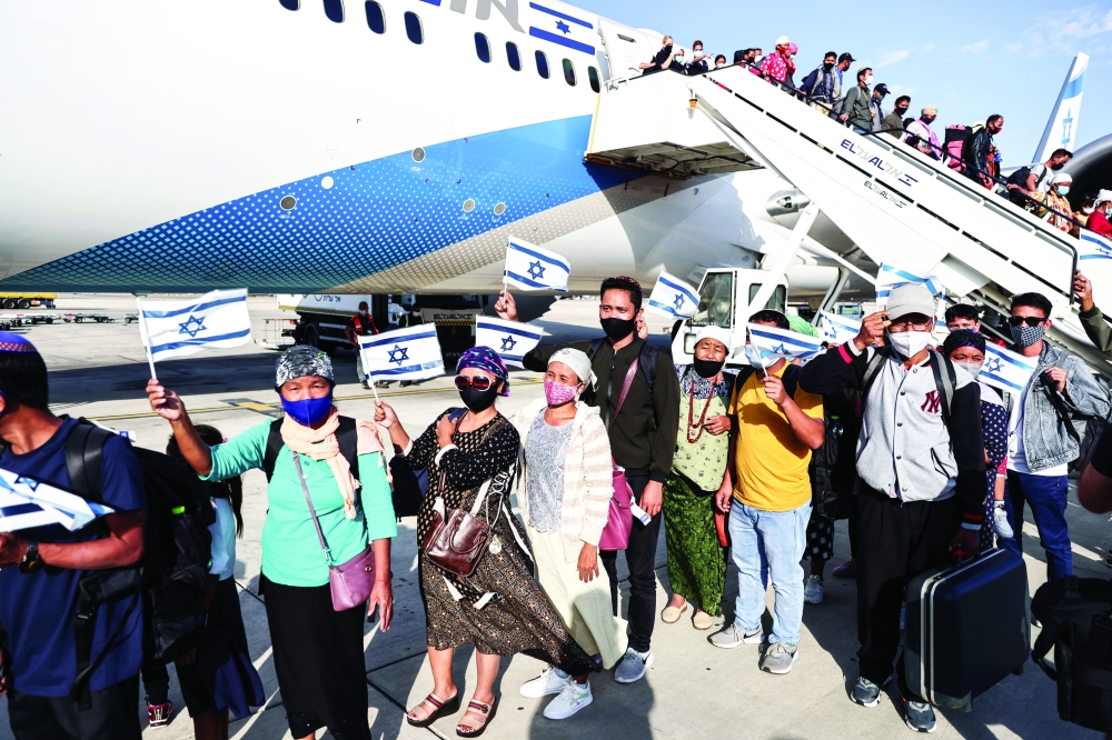 مهاجرون يهود وصلوا حديثًا من الهند للاستيطان في الاراضي الفلسطينية المحتلة يلوحون بأعلام الكيان المحتل بجوار الطائرة في مطار بن غوريون.أمس .رويترز