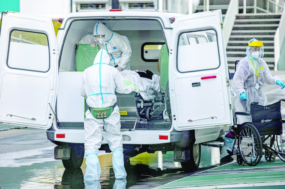 طاقم طبي ينقل مصابا بفيروس كورونا إلى مستشفى كوموناركا خارج موسكو أمس.  (أ ف ب)