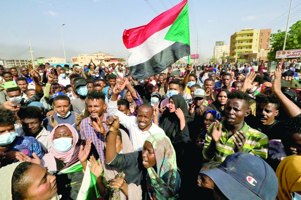 متظاهرون سودانيون يرفعون الأعلام الوطنية أثناء تجمعهم في شارع الستين بالعاصمة الخرطوم للتنديد باعتقالات الجيش لأعضاء الحكومة أمس.أ.ف.ب