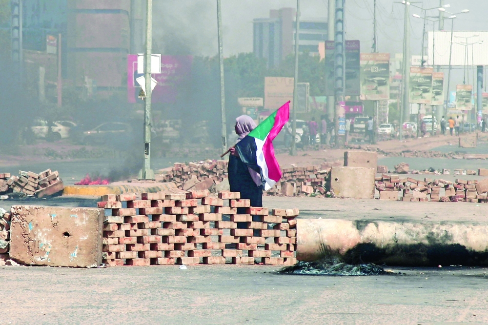 متظاهرة سودانية تحمل علم بلادها قرب حواجز أقامها المتظاهرون في أحد شوارع العاصمة الخرطوم، امس.      ا ف ب