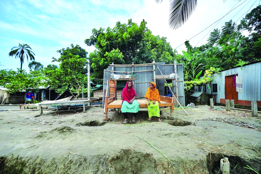 نساء يجلسن على طول منزل فارغ بعد الانتقال بسبب التهديد الناجم عن تآكل النهر على ضفاف نهر بادما في مانيكغونج. بنغلاديش .أ.ف.ب