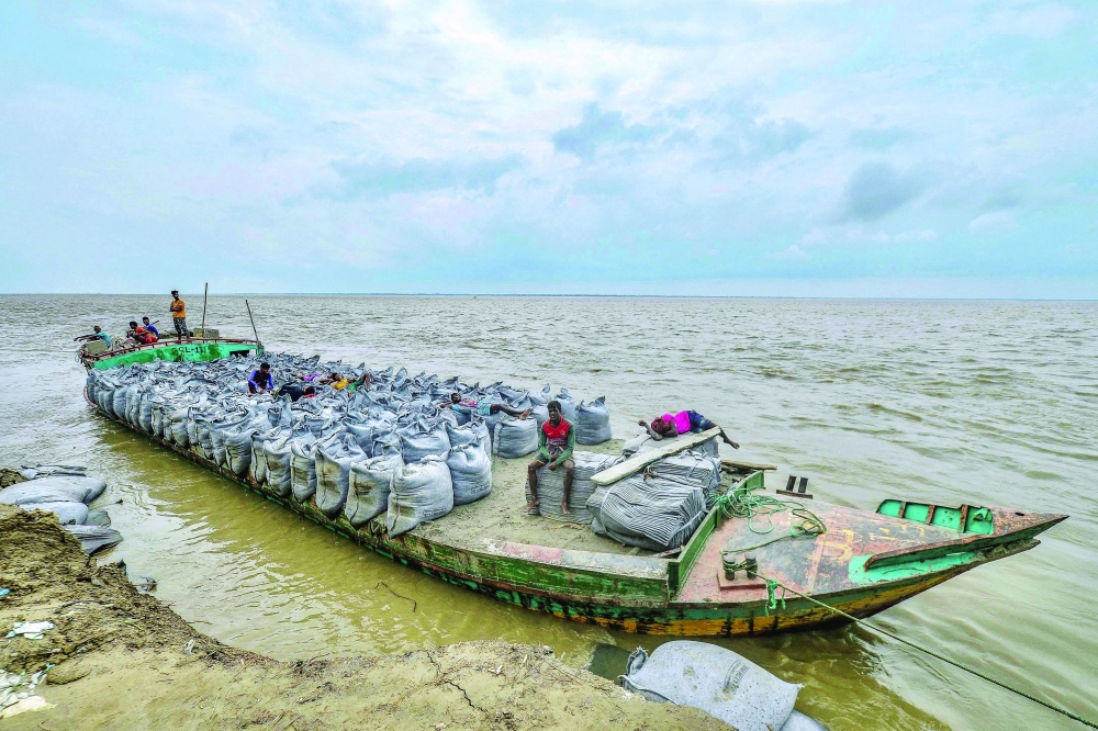 قارب يحمل أكياس منسوجات جغرافية تستخدم لمنع مراسي التعرية على ضفاف نهر بادما في مانيكونج. بنغلاديش .أ.ف.ب