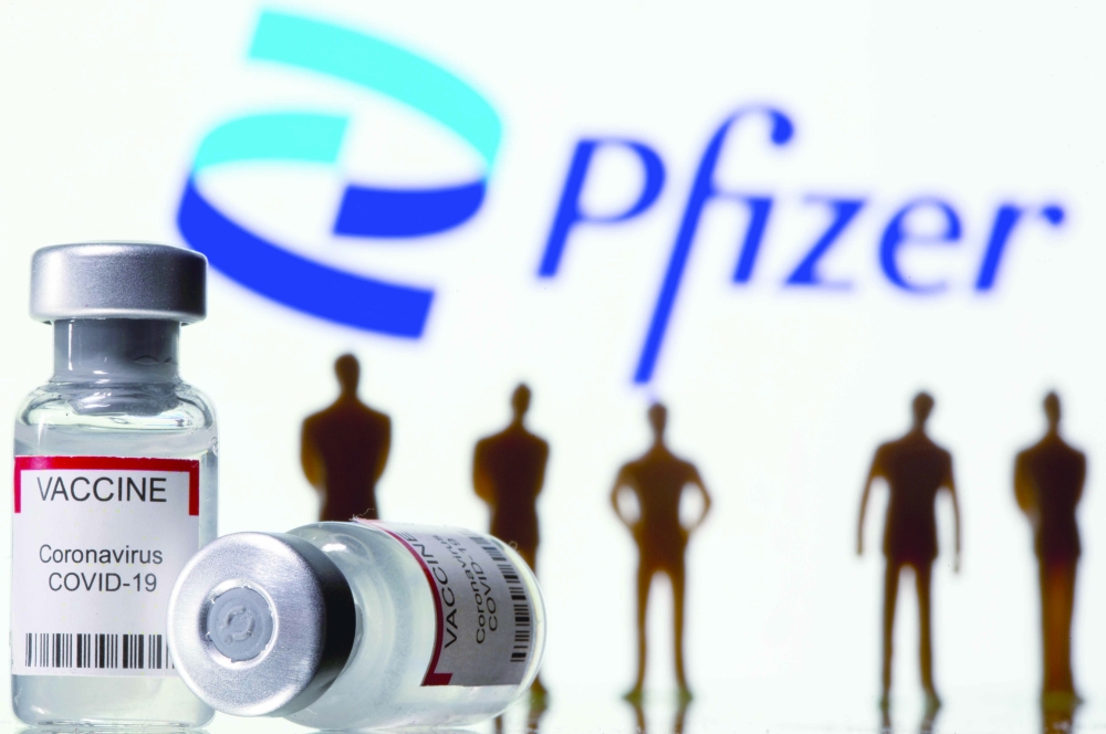 حقنة وقارورة وشخصيات وهمية أمام شعار لقاح فايزر ضمن رسم توضيحي.      (رويترز)