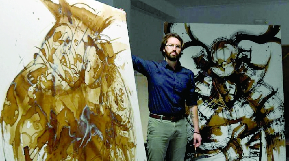 الرسام ديفيد كريماذي بجانب لوحات مرسومة بالقهوة في الاستوديو الخاص به