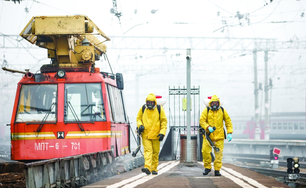 عاملون صحيون يقومون بعمليات تعقيم في محطة قطار في موسكو.   رويترز 