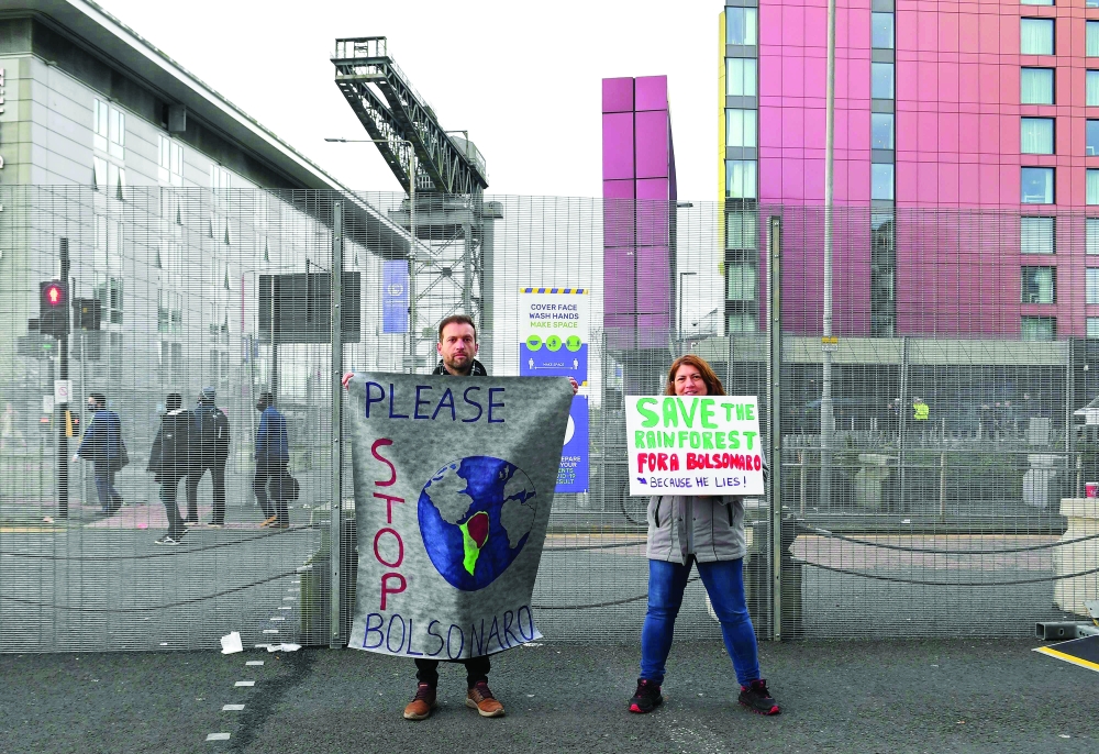 متظاهرون يحملون لافتة ضد الرئيس البرازيلي، خلال انعقاد مؤتمر الأمم المتحدة لتغير المناخ في جلاسكو، اسكتلندا، أخذت الصورة بتاريخ 2 نوفمبر 2021.ا ف ب