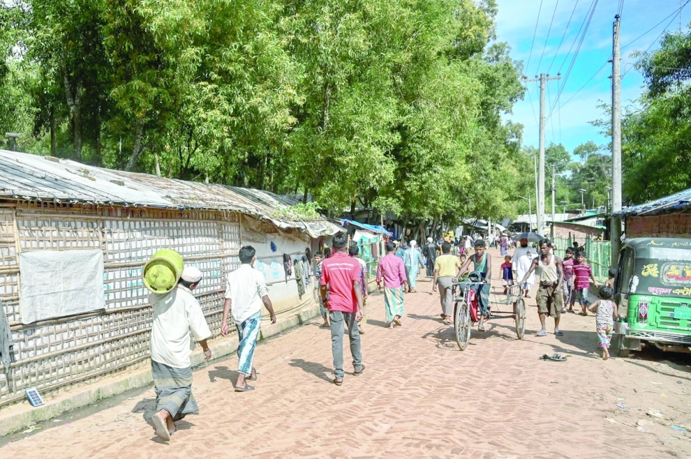 لاجئون يسيرون بالقرب من مكتب زعيم الروهينجا الناشط مهيب الله الذي قُتل برصاص مسلحين في أواخر سبتمبر في مخيم ببنغلاديش. (أ ف ب)