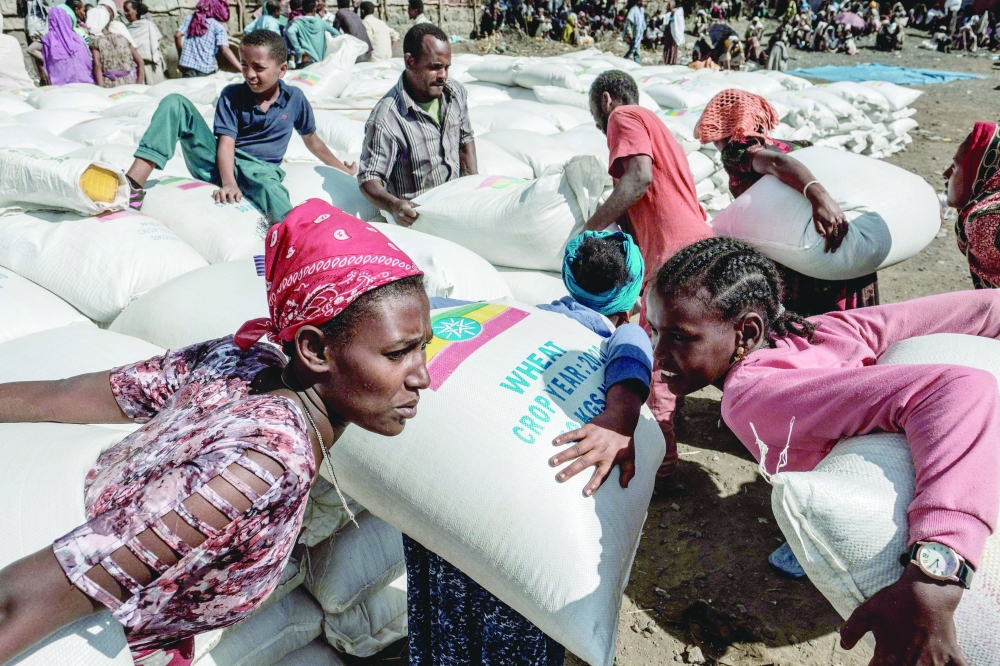 نساء يحملن أكياس قمح أثناء توزيع أغذية نظمته الحكومة الإثيوبية في مدينة ألاماتا جنوب تيجراي، ارشيفية.         ا ف ب  