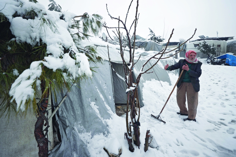 مسن سوري يزيل الثلج من امام خيمته.  ا ف ب