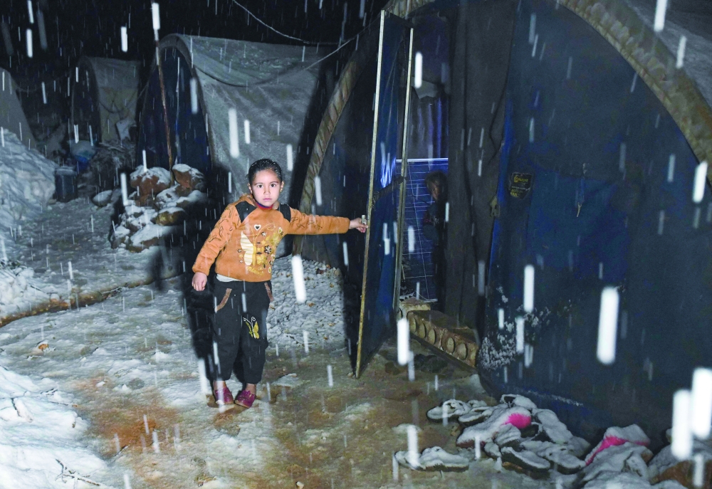 طفلة تقف بجانب خيمتها وسط تساقط  كثيف للثلوج، في مخيم للنازحين بريف عفرين بمحافظة حلب.   ا ف ب